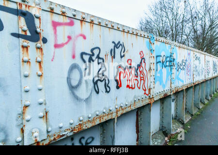 Ugly graffiti on a typical old iron railway footbridge in Woking, Surrey, south-east England, UK Stock Photo