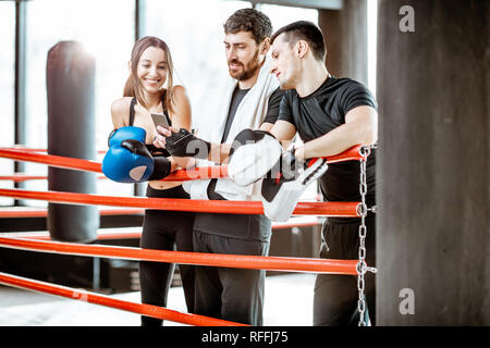 Young active friends having fun, standing together after the training on the boxing ring at the gym Stock Photo