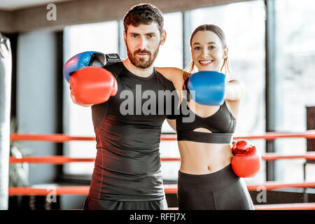 Portrait of an athletic couple in sportswear with boxing gloves hugging together on the boxing ring at the gym Stock Photo