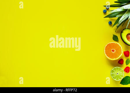 Creative layout made of various tropical fruits. Flat-lay of pineapple, banana, orange, lime, avocado, raspberry, blueberry on yellow background. Food Stock Photo