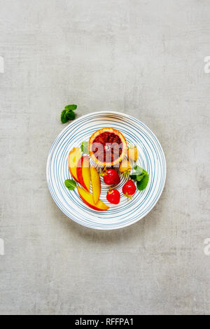 Fresh fruits and berries in plate on light background flat lay. Food concept. Top view Stock Photo