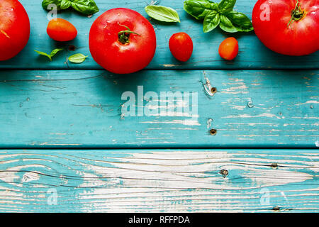 Fresh tomato and basil leaves on wood flat lay. Stock Photo