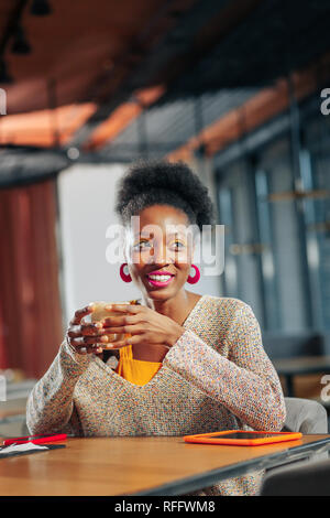 Dark-eyed woman wearing oversized sweater drinking latte Stock Photo
