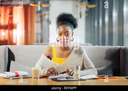 Dark-eyed international student feeling tired and busy while studying Stock Photo