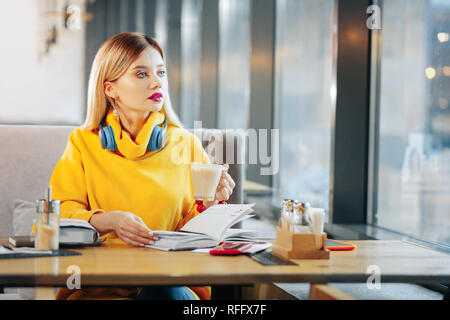 Beautiful blue-eyed woman holding cup with tasty latte Stock Photo
