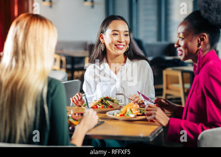 Three friends eating delicious salads in their favorite restaurant Stock Photo