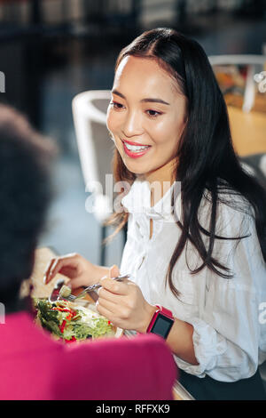 Beautiful dark-eyed woman wearing white blouse talking to her friend Stock Photo