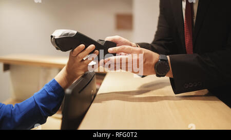 Hotel Guest Paying Business Travel With Credit Card and POS Stock Photo