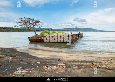 A colorful landscape photo of a old rusty sunken ship wreck covered with vegetation at the beach of Puerto Viejo, Limon, Costa Rica. Stock Photo