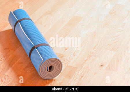 Rolled up blue yoga mat on the floor. Healthy lifestyle concept Stock Photo