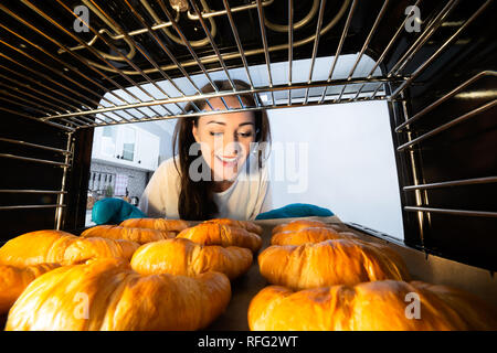 Smiling Young Woman Looking At Fresh Baked Croissants In Oven Stock Photo