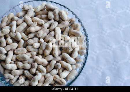 Peanuts in group on a tray of glass on table with silver cloth Stock Photo