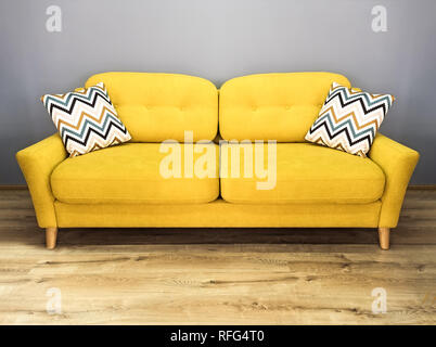 Green lemon yellow sofa with pillow. Soft lemon couch. Modern divan in interior gray wall wooden floor. Stock Photo