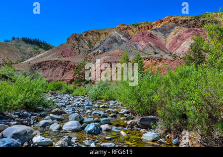 View of unrealy beautiful colorful clay cliffs in Altai mountains, Russia. Summer landscape, which is called Martian and creek running between stones  Stock Photo