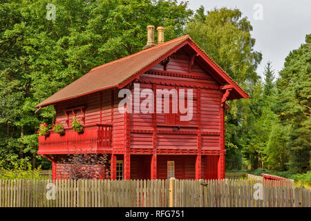 RED CHALET HOUSE GORDON CASTLE ESTATE FOCHABERS SCOTLAND SURROUNDED BY TREES IN SUMMER Stock Photo