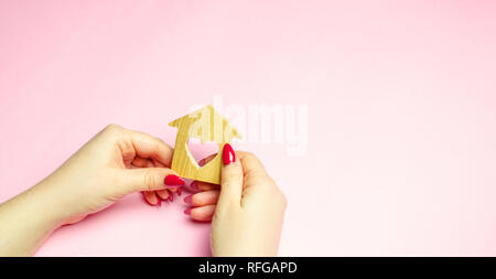 A girl holds a house and heart in her hands. The concept of affordable housing. A dream is to buy a house. Accumulation on the apartment. Property ren Stock Photo