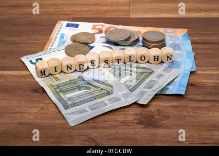 Die Euro Geldscheine und Münzen liegen auf dem Tisch mit dem Wort Mindestlohn Stock Photo