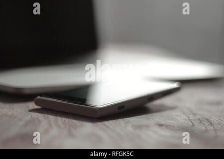close up. blurred image of a mobile phone and laptop on the desktop Stock Photo
