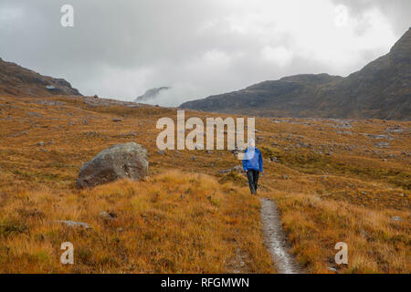 A person walking in Scottish countryside near the Allt Coire Rooill river in Torridon, Scotland Stock Photo