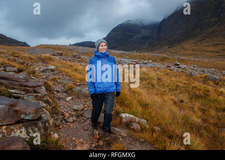 A person walking in Scottish countryside near the Allt Coire Rooill river in Torridon, Scotland Stock Photo