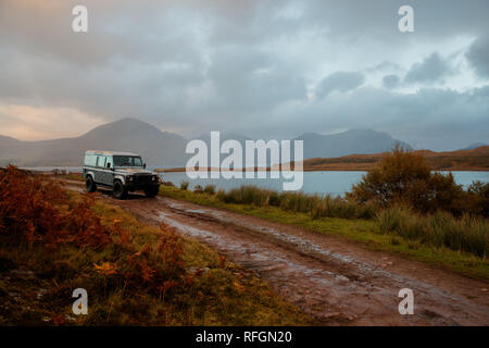A Land Rover on a dirt track in the countryside of Scotland at dusk Stock Photo