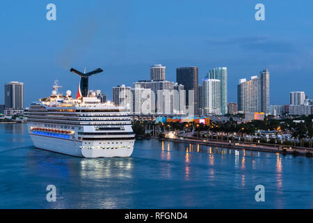 Miami, Florida - November 19 2018: Carnival Victory Cruise Ship sailing in the Port of Miami at sunrise with skyline of downtown Miami in the backgrou Stock Photo