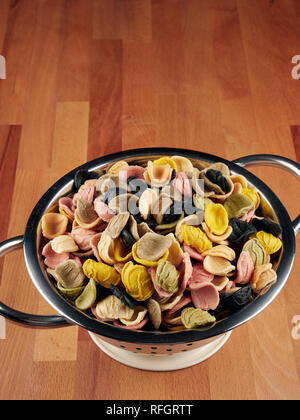 Colorful uncooked orecchiette pasta in a small colander Stock Photo