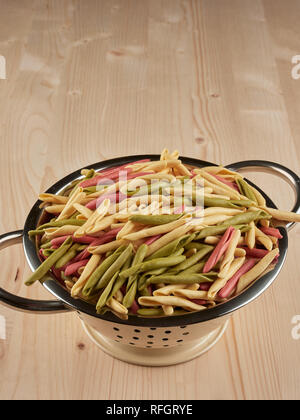 Colorful uncooked orecchiette pasta in a small colander Stock Photo