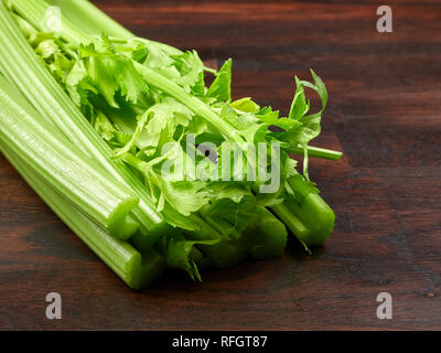Fresh green celery stalks on a dark rustic wooden oak board Stock Photo