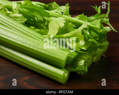 Fresh green celery stalks on a dark rustic wooden oak board Stock Photo