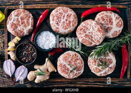 meat delicatessen - raw Atriaux of ground pork wrapped in caul fat, swiss cuisine, type of bratwurst on a wooden tray with spices and salt, on a woode Stock Photo