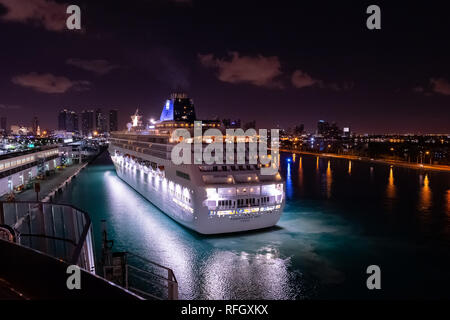 Miami, Florida - November 19 2018: Norwegian Sky Cruise Ship sailing in the Port of Miami just before sunrise with skyline of downtown Miami Stock Photo