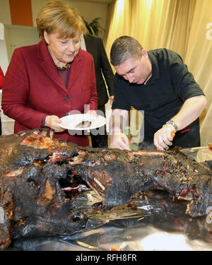 Trinwillershagen, Germany. 25th Jan, 2019. Angela Merkel (CDU), Chancellor of the Federal Republic of Germany, is having Andre Teuerung, butcher, give her a piece of roast wild boar at the traditional New Year's reception of the district of Vorpommern-Rügen. Merkel has represented the constituency in the Bundestag with a direct mandate since 1990. Credit: Bernd Wüstneck/dpa/Alamy Live News Stock Photo