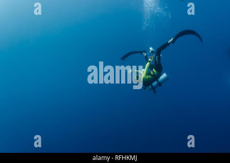 Scuba diver spins in a somersault head over heals as he descends into the blue depths Stock Photo