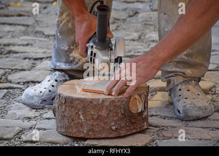 Close up of working man cutting and shaping ceramic tile with angle grinder Stock Photo