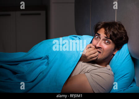 Young man scared in his bed having nightmares Stock Photo