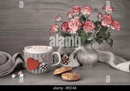 Valentines day still life with cup of hot chocolate with marshmallows, pink roses, greeting card and warm scarf Stock Photo