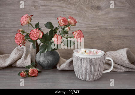 Valentines day still life with cup of hot chocolate with marshmallows, pink roses and warm scarf Stock Photo