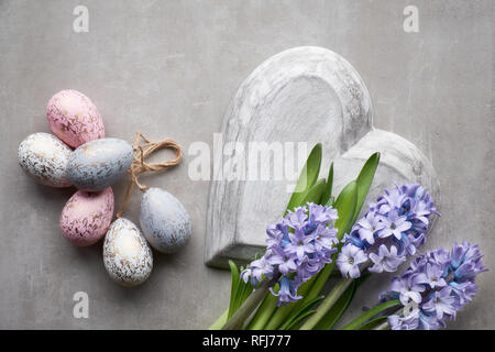 Easter flat lay with blue hyacinth flowers, easter eggs and large heart on light stone background