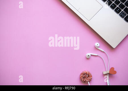 Workspace in pink trendy color. Laptop and headphones close by. Beginning of the holiday or the onset of Valentine's Day or another love event. Near t Stock Photo