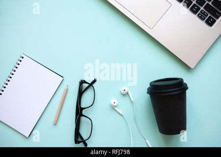 Workspace in a trendy blue color. Many different things including a laptop and headphones are on the table. Stock Photo