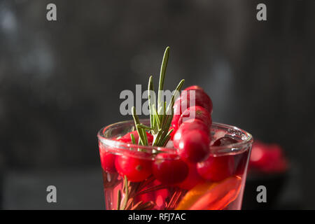 Cocktail cranberries and rosemary leaf on black background. Stock Photo