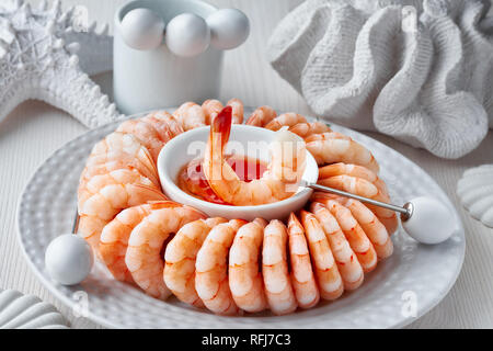 Close-up on shrimp ring with sweet chili sause on light background with white sea decorations Stock Photo