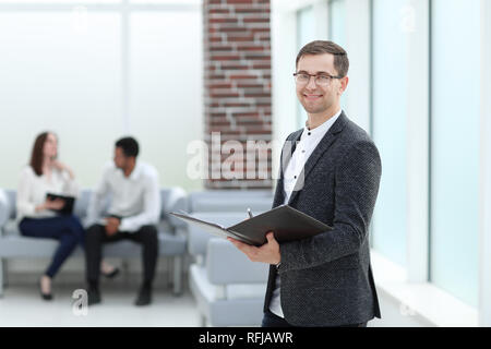 smiling business man reading business documents standing in the office Stock Photo
