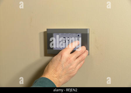 Hand adjusting temperature on digital programmable thermostat Stock Photo