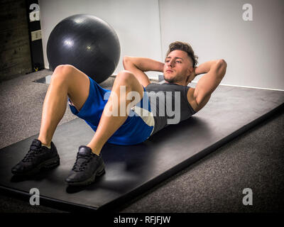 Handsome young man doing abs exercises on mat Stock Photo