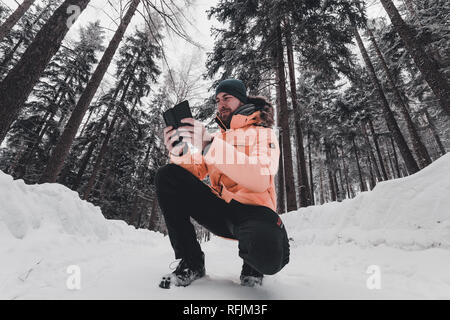 Back view closeup of Person wearing yellow jacket and hat, walking in beautiful winter season full of trees alone, ground covered by too much snow, he Stock Photo