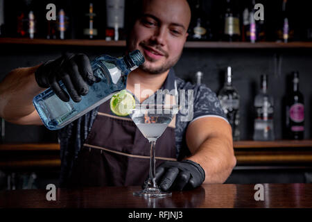 barman preparing and pouring cocktail in martini class. Stock Photo