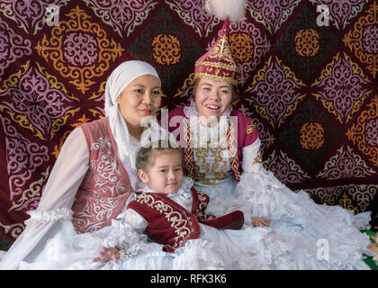 Three generations of happy women in traditional attire in a yurt, Almaty, Kazakhstan Stock Photo