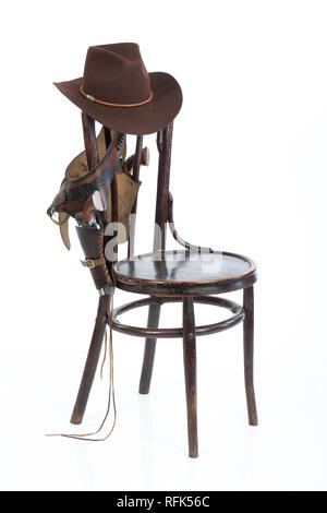 Cowboy belt, guns and hat on an old chair on isolated background Stock Photo